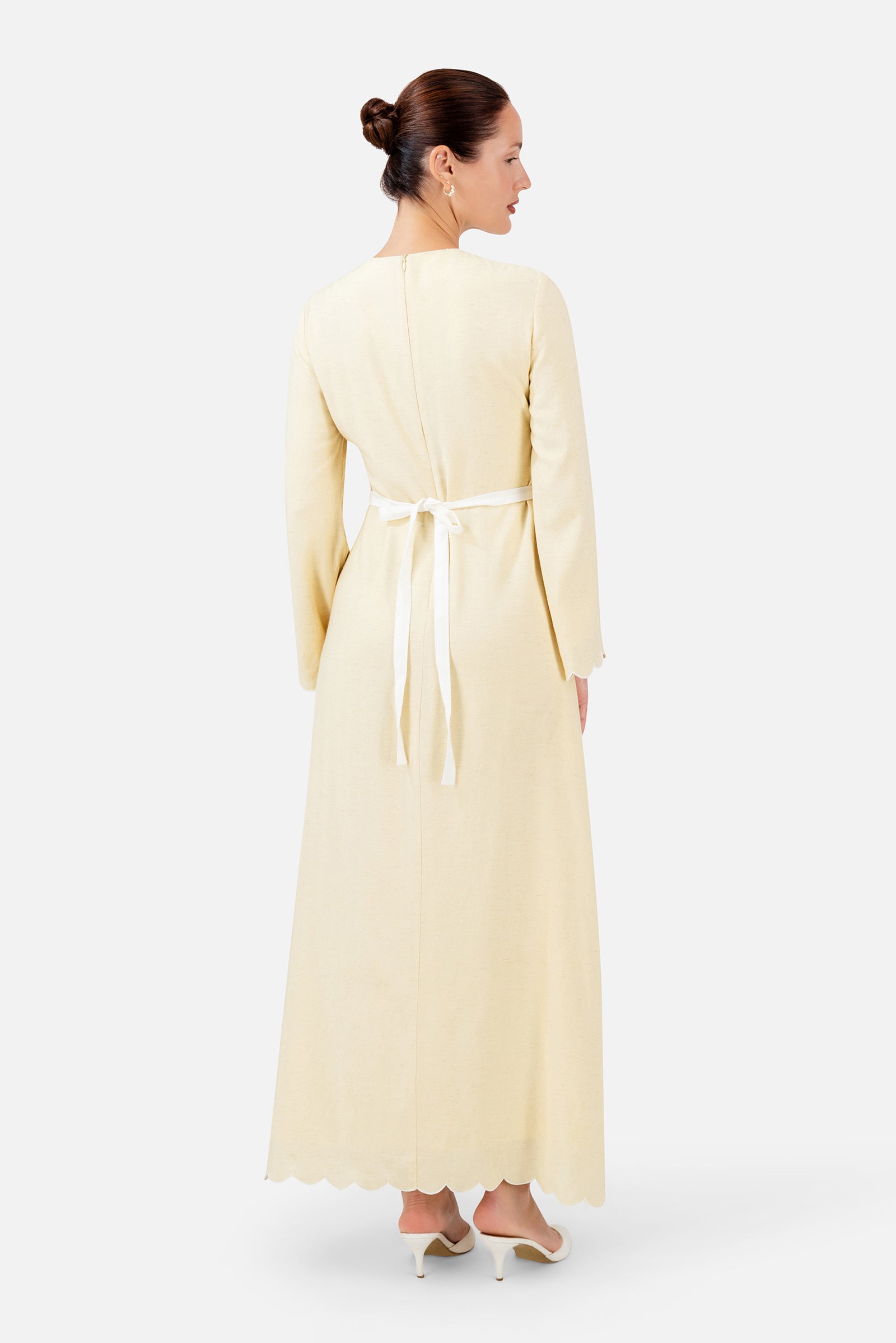 FARES Belt Detail Scalloped Dress in Buttercup shown from the back, highlighting the long silhouette and elegant belt detail.