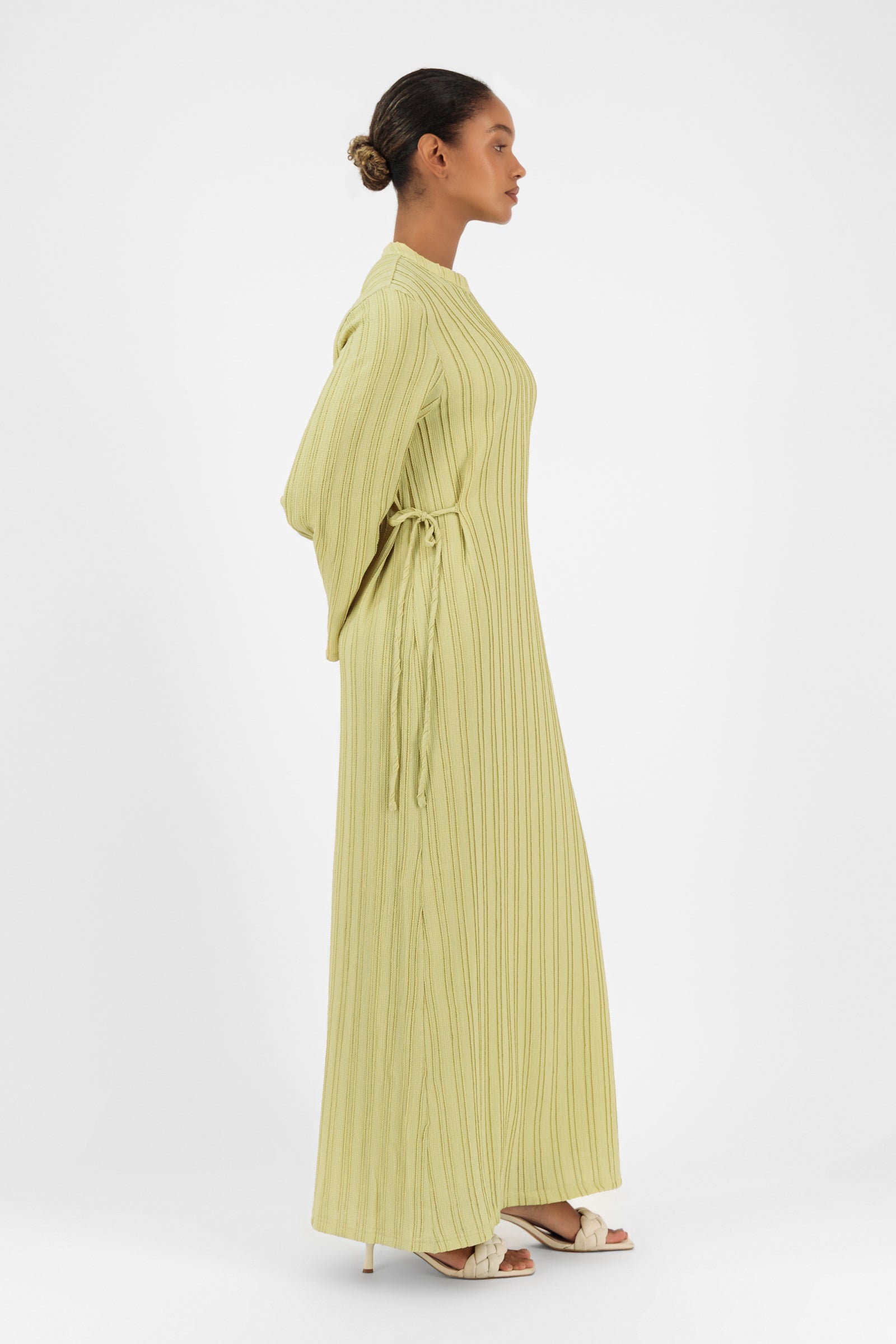 Side profile of the FARES Textured Bow Detail Dress in Lime showcasing the graceful drape of the maxi dress.