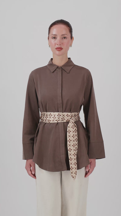 A woman showcases the FARES Printed Wrap Belt Button Up in Mocha, highlighting the fit and movement of this long-sleeve shirt with its statement wrap belt.