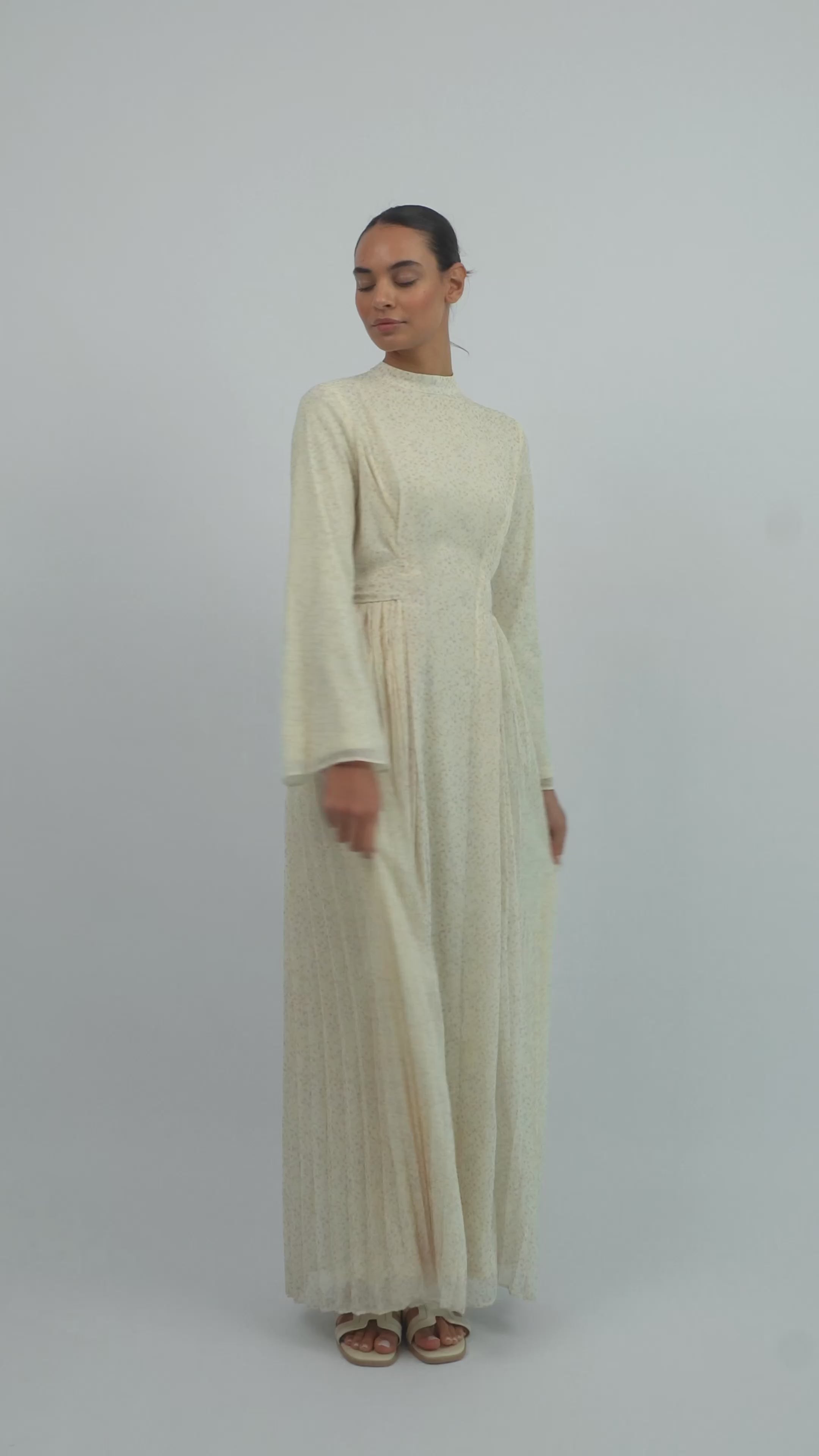 Model walking in the FARES Printed Tie Dress with Pleats, showing the graceful movement and flowing pleats of the printed dress.