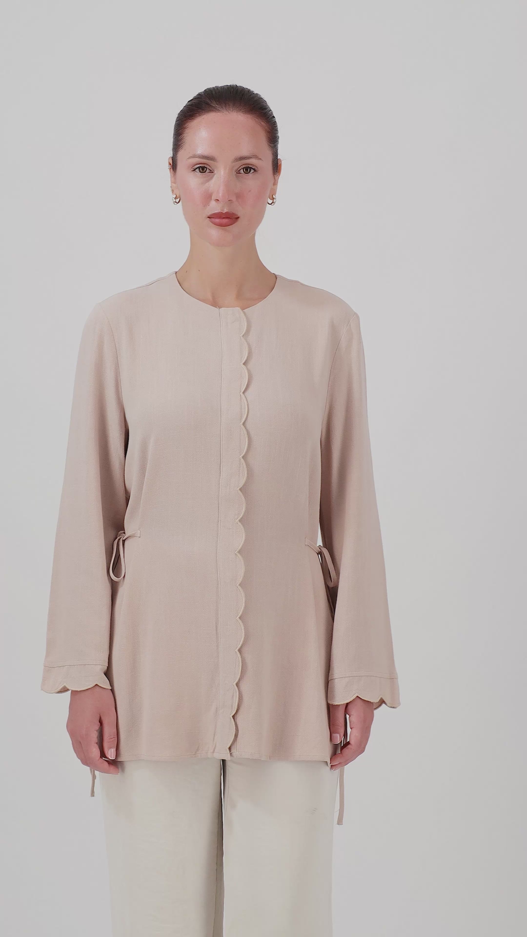 A woman walks in the FARES Scalloped Detail Linen Blend Top in Shell, showcasing the relaxed silhouette and natural movement of this linen top.