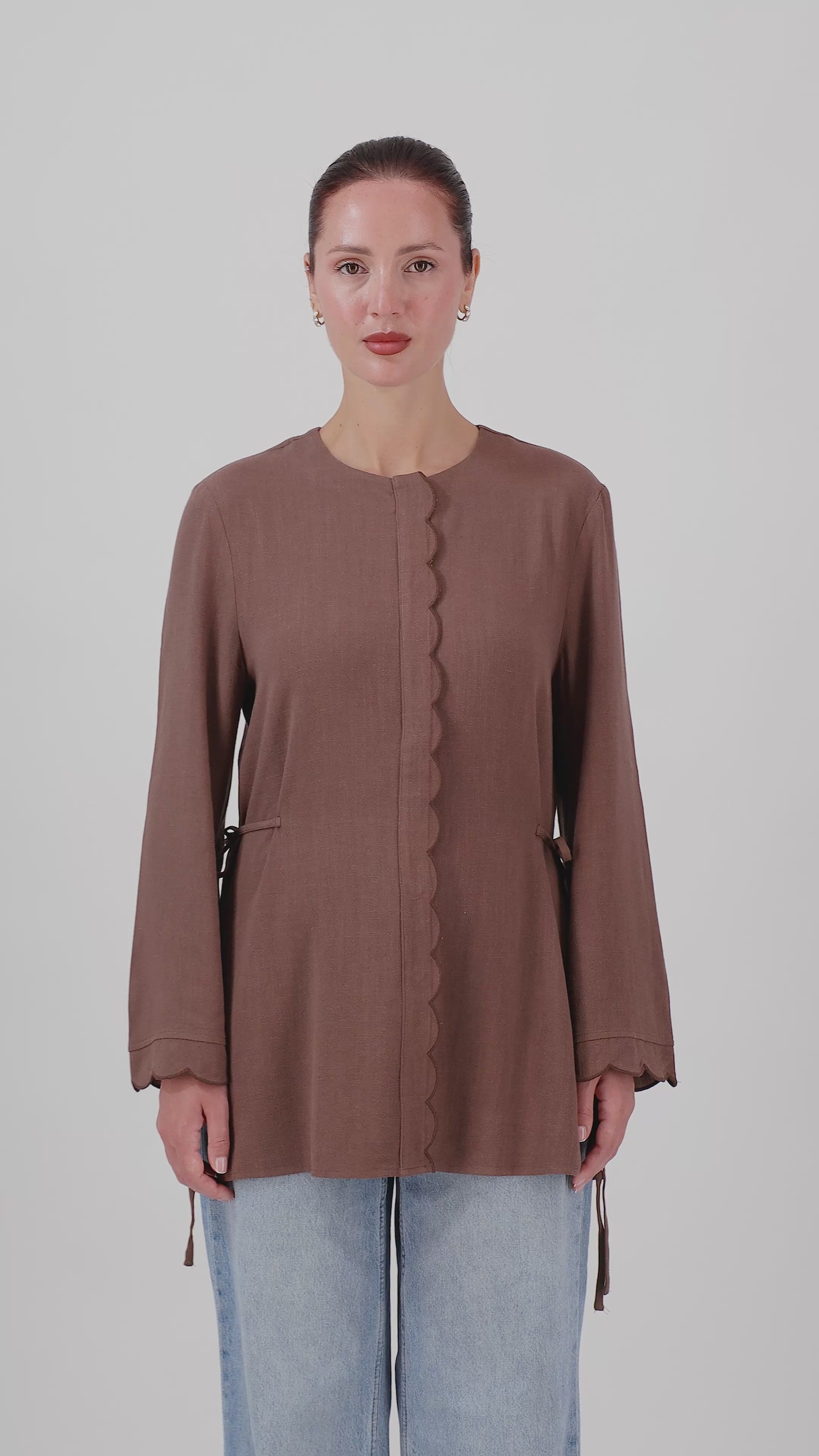 A woman walks in the FARES Scalloped Detail Linen Blend Top in Fudge, showcasing the relaxed silhouette and natural movement of this linen top.