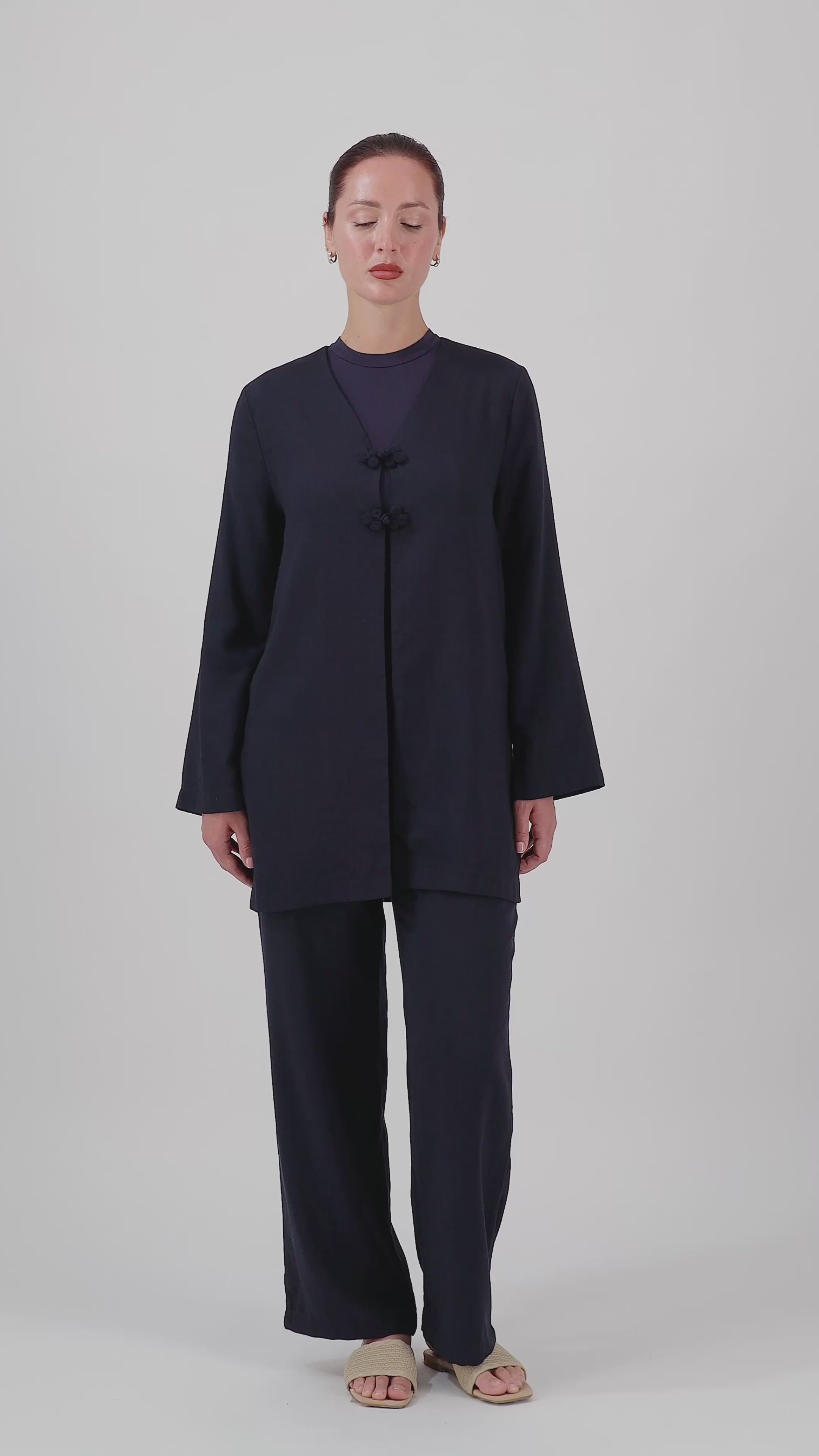 A model walks in the FARES Knot Detail Cardigan in Navy, showcasing the relaxed silhouette and natural movement of this wide-sleeve cardigan.