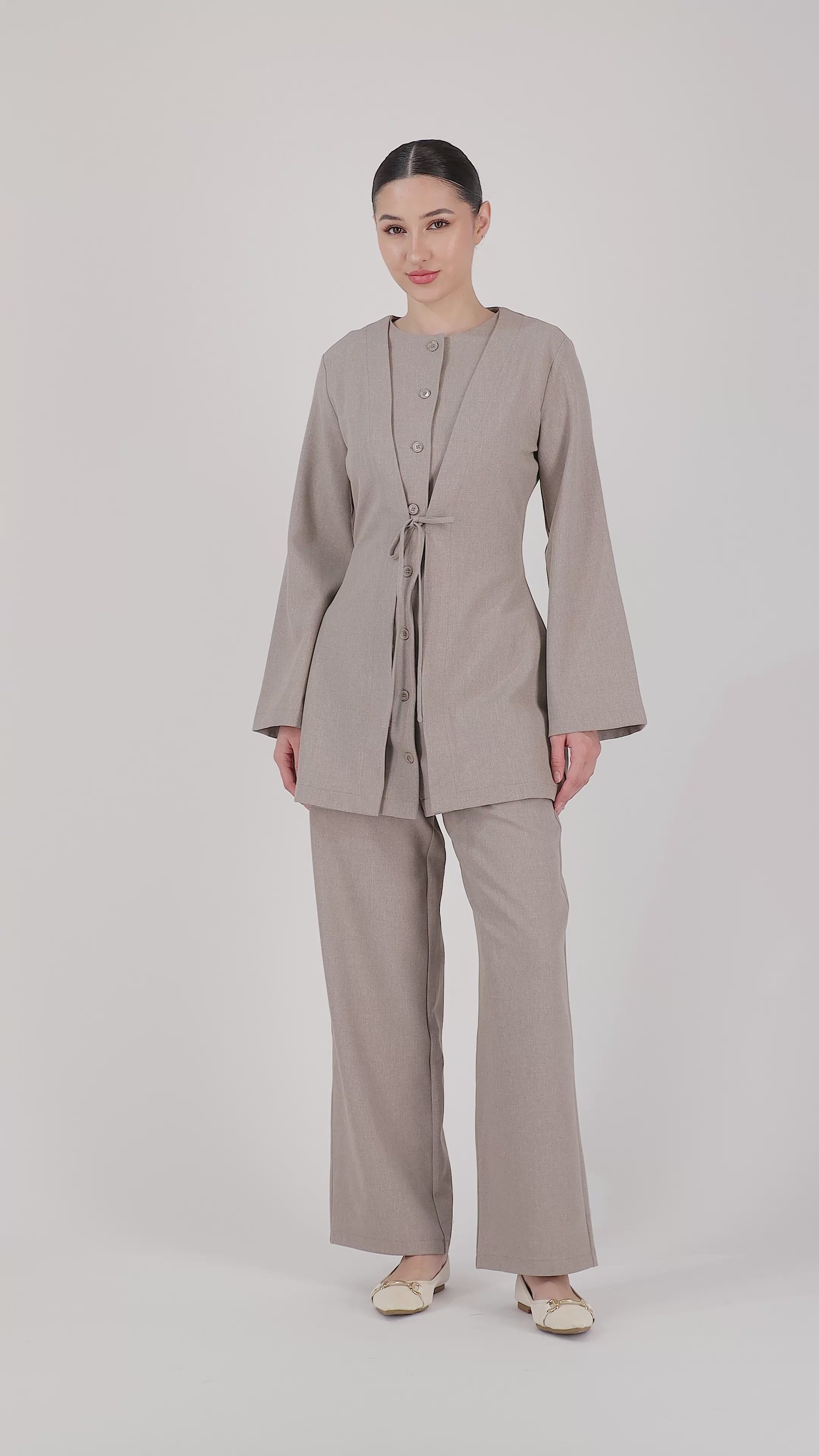 A model walks naturally in the FARES Tailored Elastic Waist Pants in Stone, showcasing the flow, comfort and relaxed movement of these wide leg elastic waist pants.