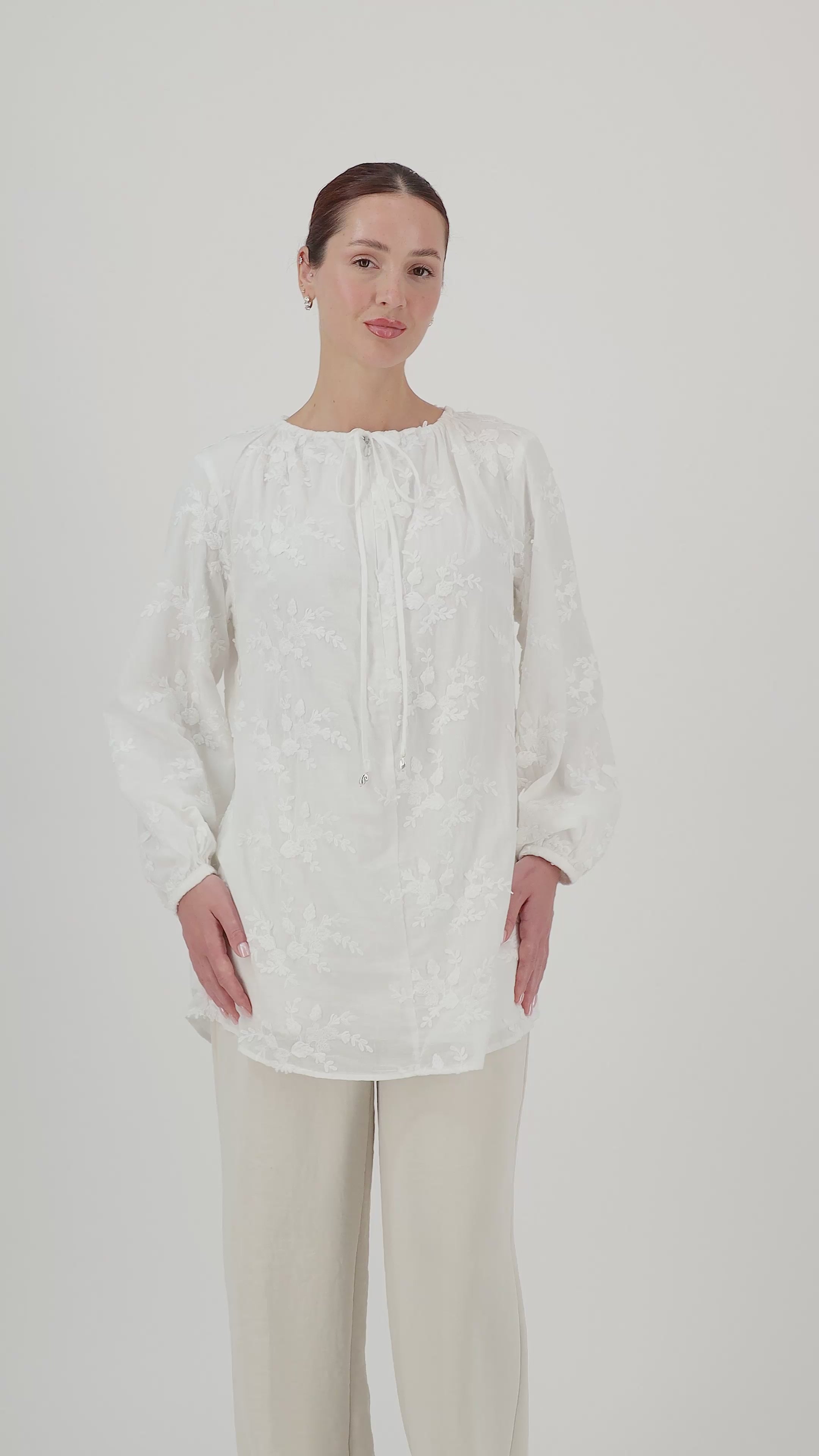  Model walks, turns from side to side and showcases the white floral embroidered blouse in motion.