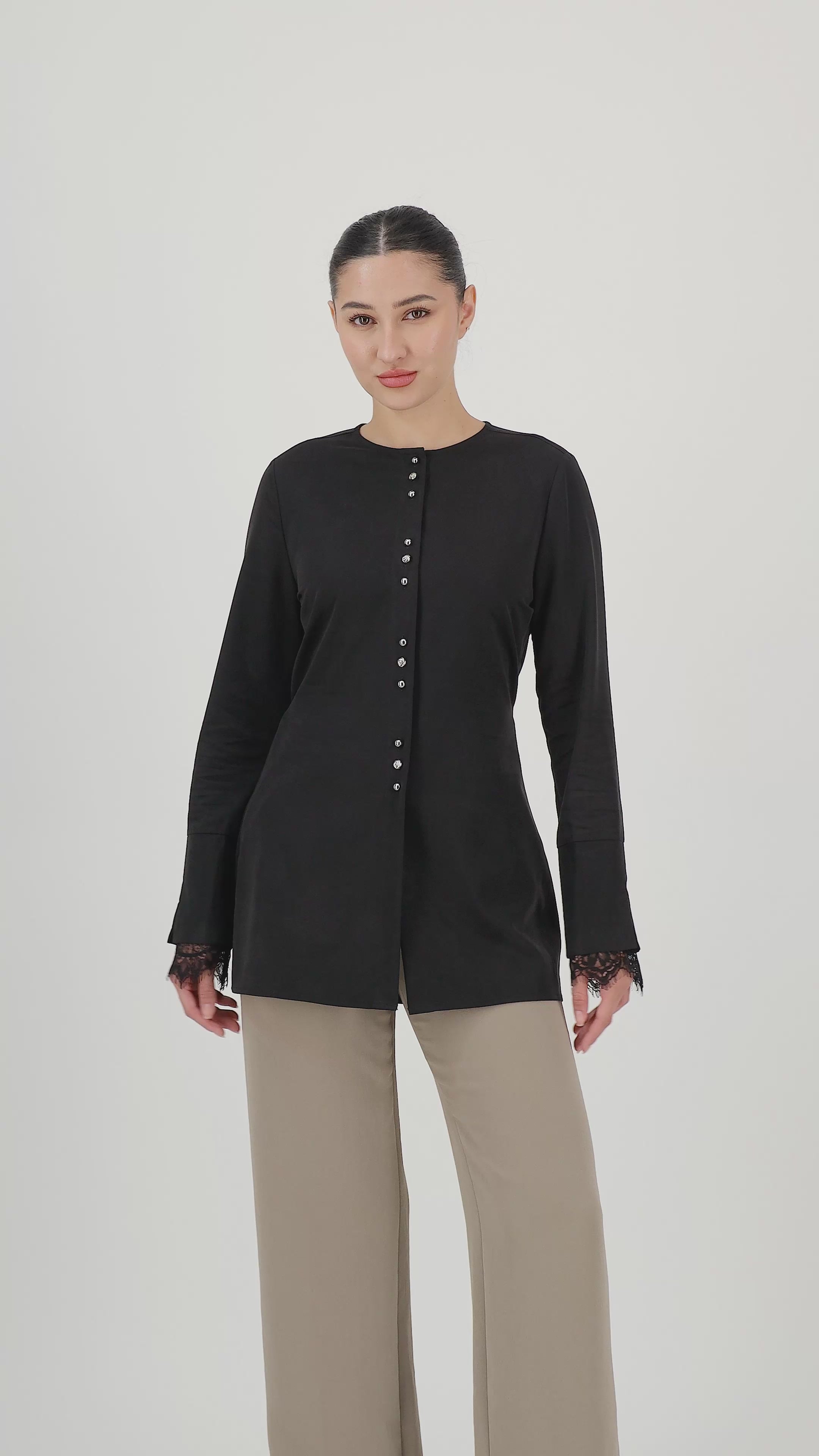 Model walks, turns from side to side and showcases the Black button-up long-sleeve top in motion.