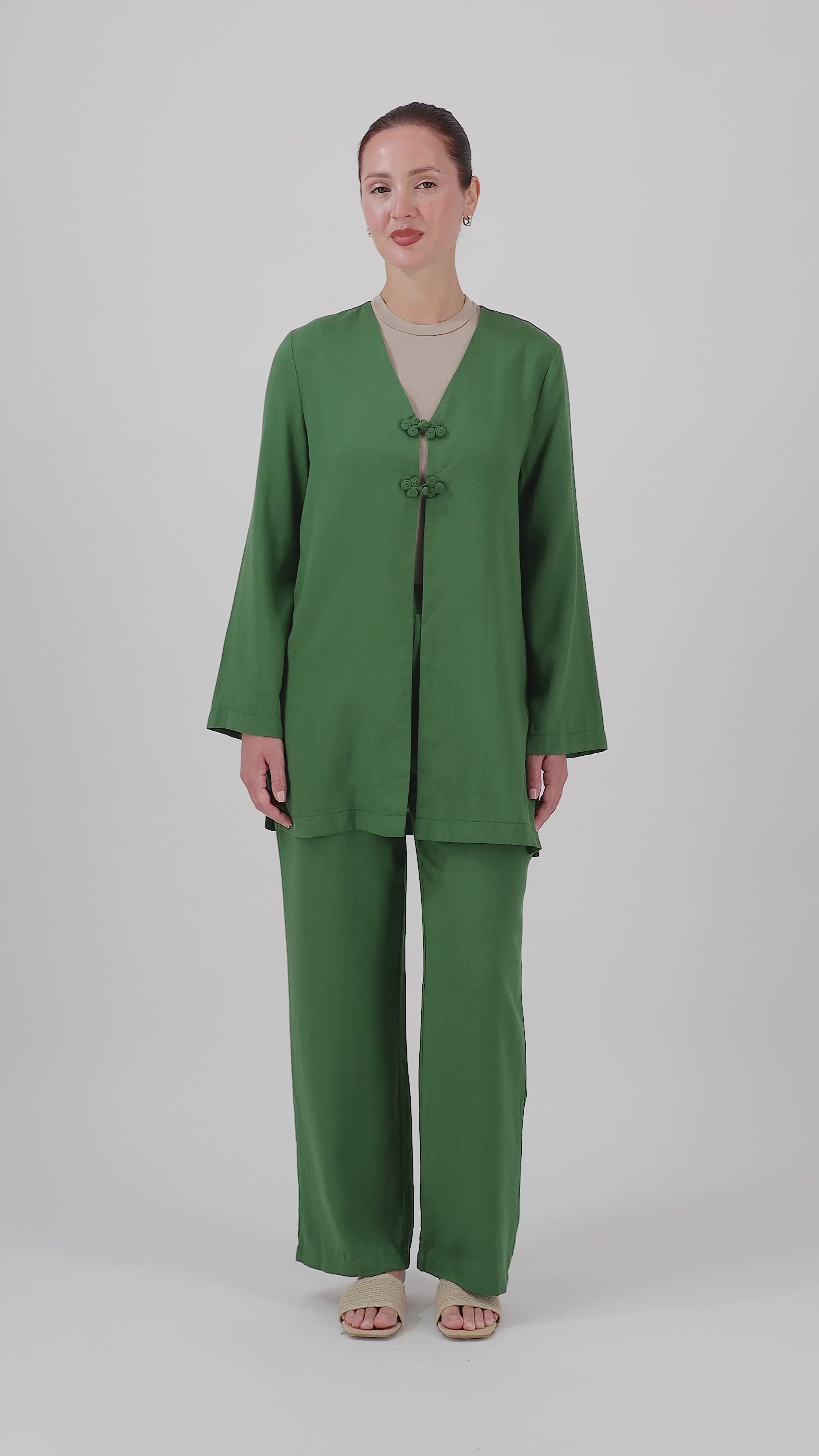 A model walks in the FARES Relaxed Fit Pants in Evergreen, showcasing the comfortable fit and natural movement of these relaxed fit pants.