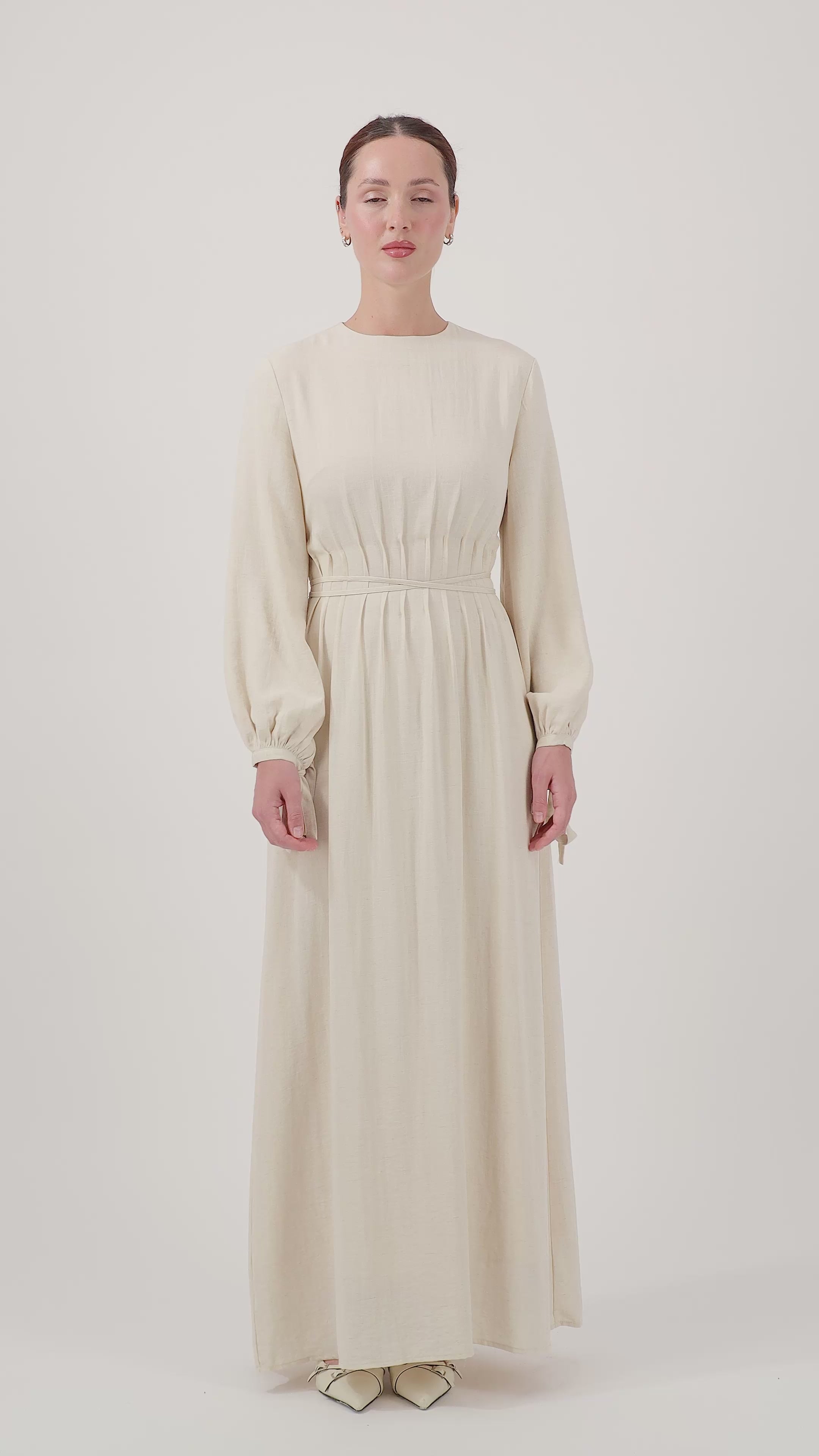 Model walking while wearing the Crema Tie Detail Darted Waist Dress, showcasing its elegant movement.