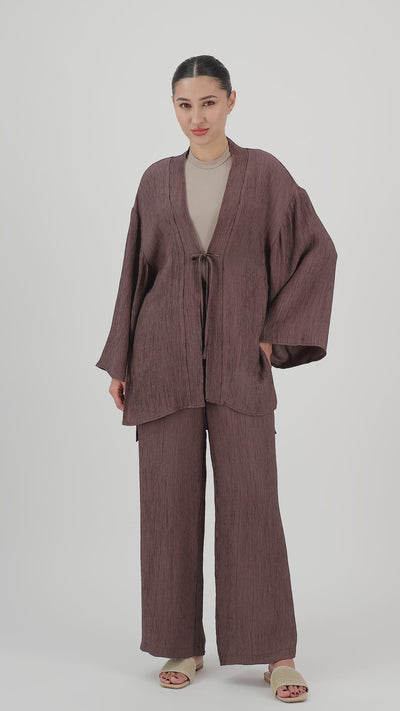 Model walks, turns from side to side and showcases the Icy Brown rippled relaxed fit pants in motion.