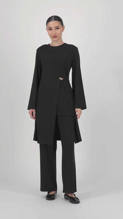 Video of the model moving in the Gold Accent Wrap Top Black, highlighting the flattering wrap fit and elegant sleeve line of this long sleeve wrap top.