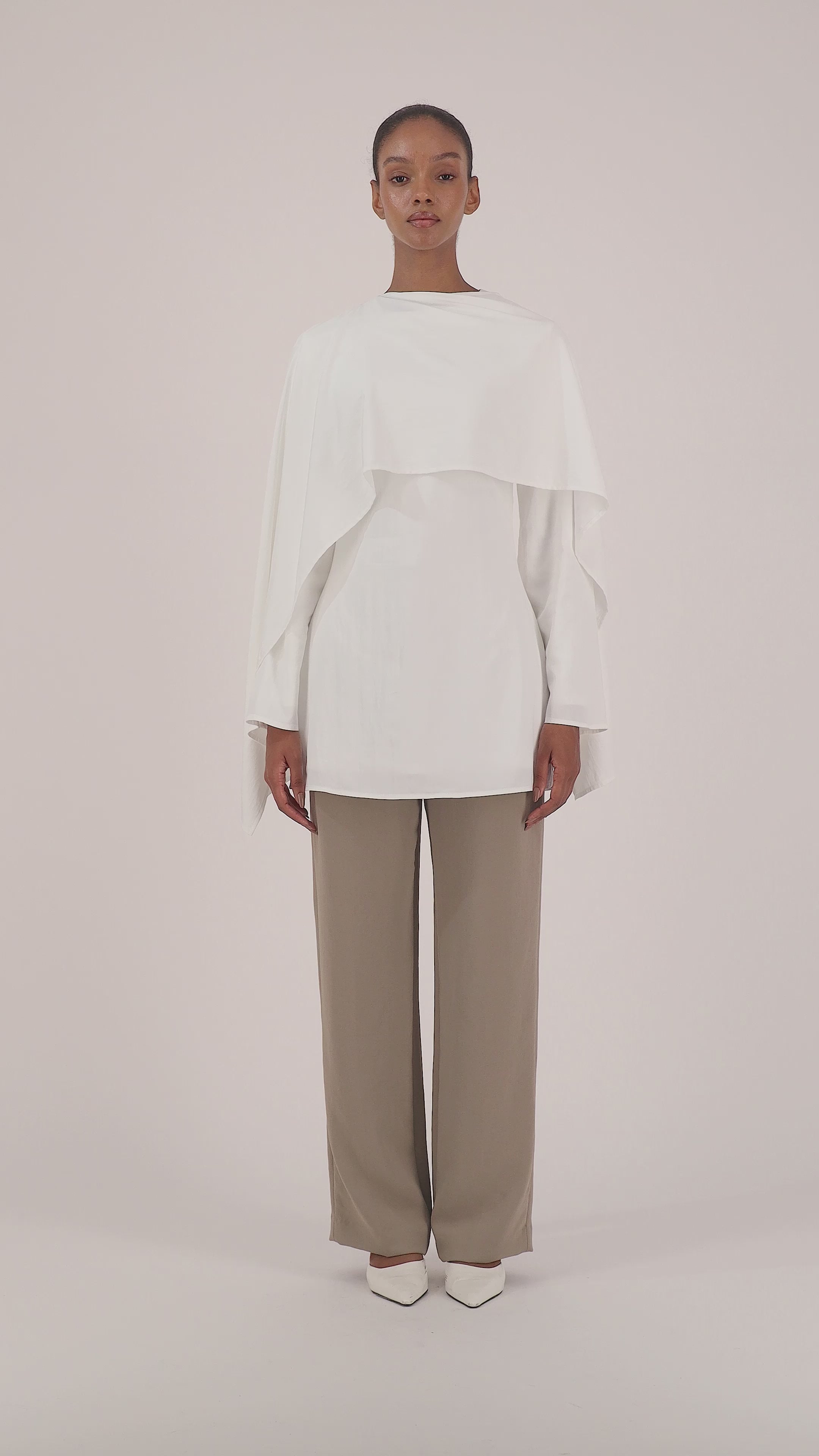 Video of a model walking in the FARES Cape Overlay Tunic in White showcasing the fluid movement and elegant shape of the tunic.