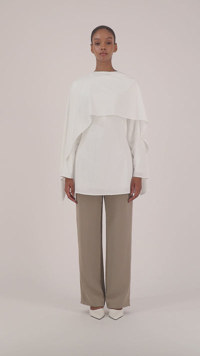 Video of a model walking in the FARES Cape Overlay Tunic in White showcasing the fluid movement and elegant shape of the tunic.